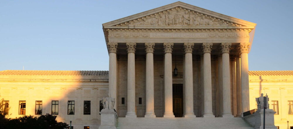 The U.S. Supreme Court, a white pillared building, at sunset.