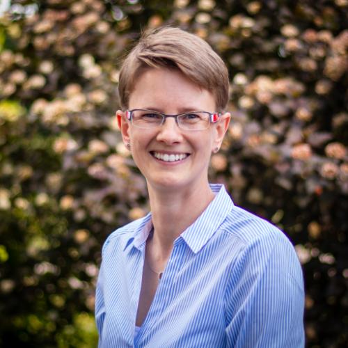Dr Steffi Hamann poses for a headshot in front of some trees.