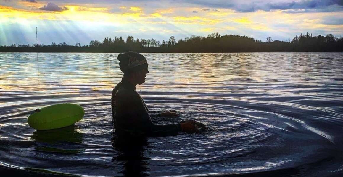 Coralee Allaert swims in a lake at sunset.