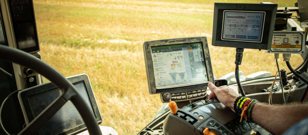 The inside of a tractor as it drives through a yellow field.
