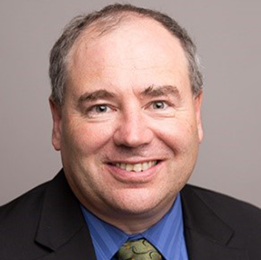 Dr. Kevin Keener smiling in front of a grey backdrop