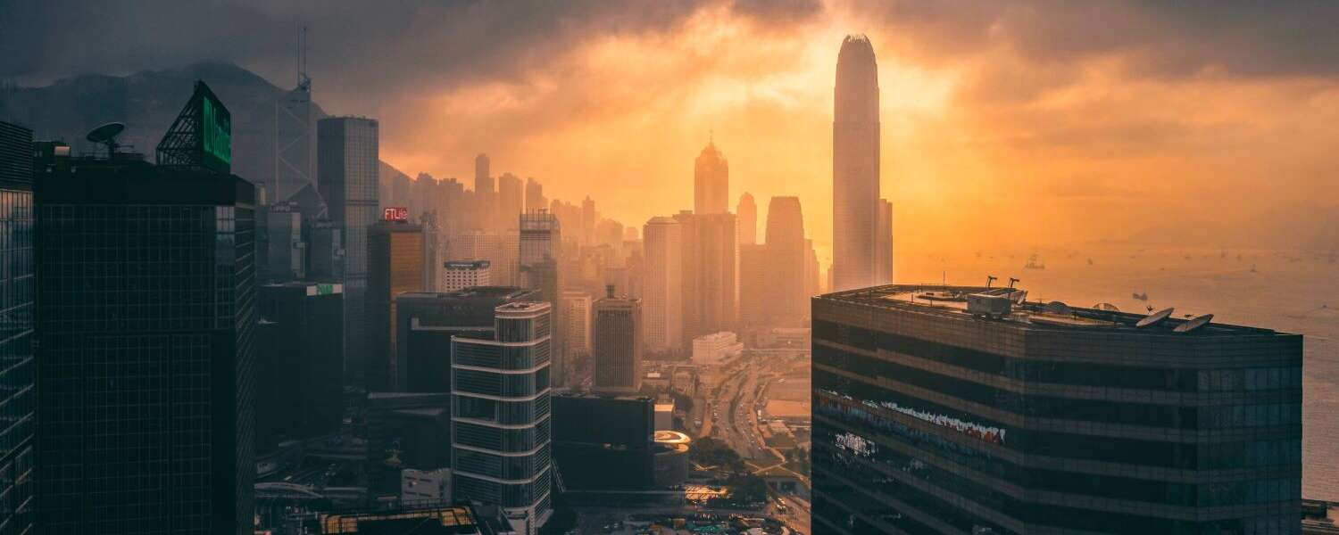 the skyline of Hong Kong with the sun rising through thick clouds