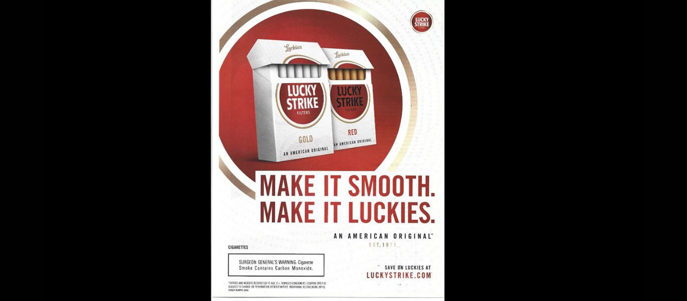 An advertisement for Lucky Strike cigarettes. In a red, gold-outlined circle, are two white cigarette packages open to display the cigarettes. Each have the Lucky Strike logo in the centre. At the bottom of the circle is large red text reading "Make It Smooth. Make It Luckies." with the words "An Amercian Original" and the establishment date below. In the bottom right hand corner the text reads "Save on Luckies at luckystrike.com". In the bottom left-hand corner is a health warning. In the top right-hand corner is the "Lucky Strike" logo.