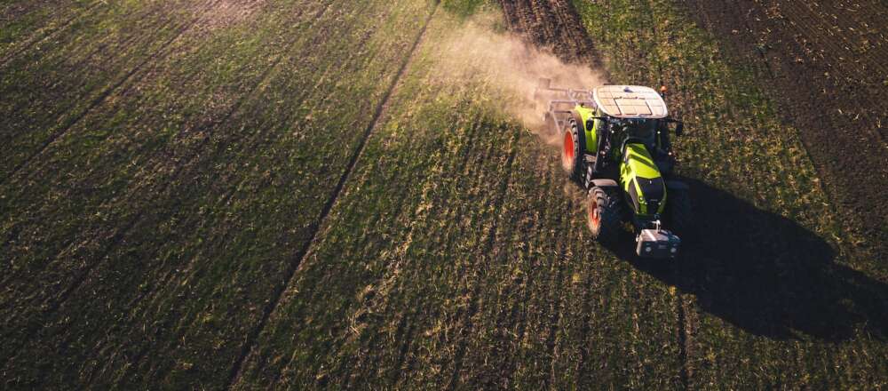 A green and white tractor on green grass field during daytime.