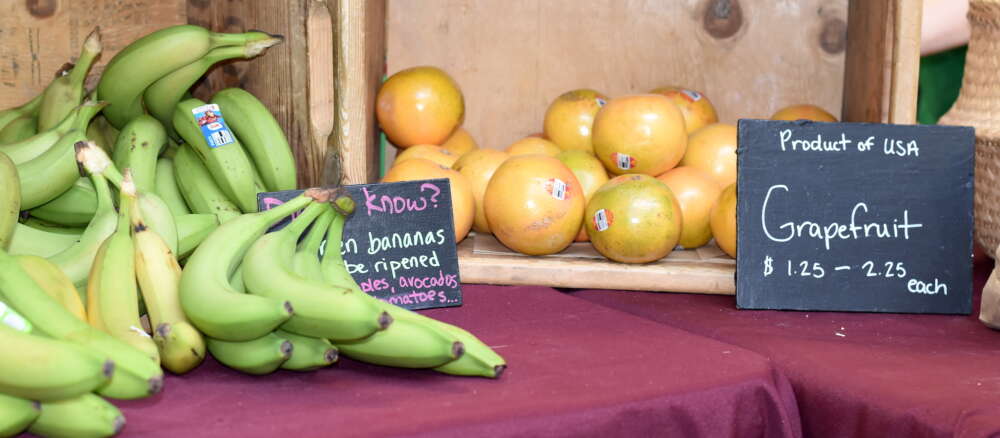 Crates of bananas and grapefruit sit on a tablecoth-covered table