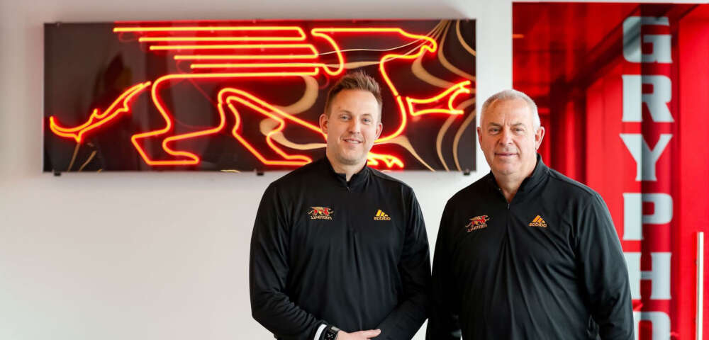 Ryan and Pat Sheahan stand against a neon Gryphons sign