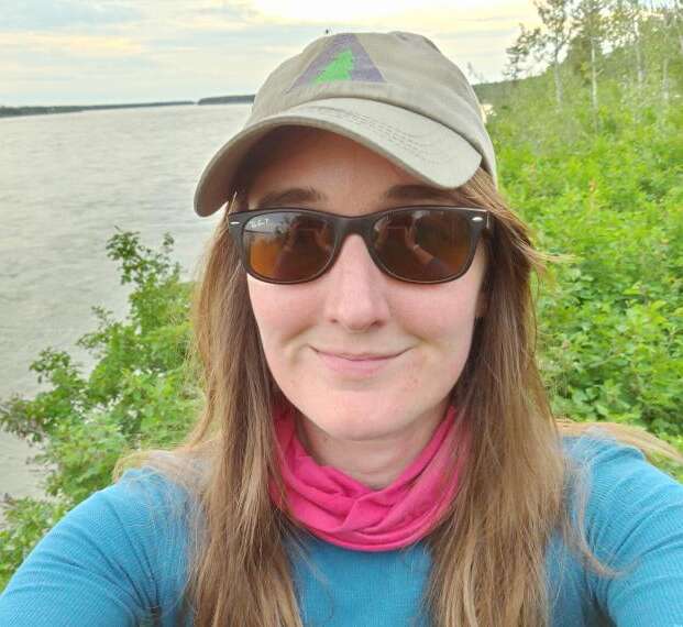 Dr. Catherine Dieleman wears a hat while standing near a river