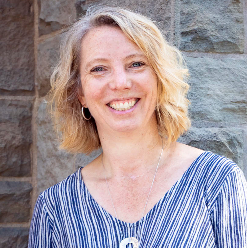 Dr. Robin Roth in front of a stone wall.