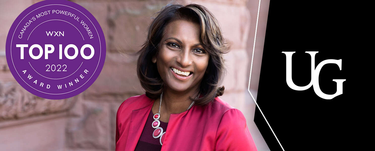 Indira Naidoo-Harris smiles near a sandstone building. The Top 100 logo is to the left; the U of G logo is to the right
