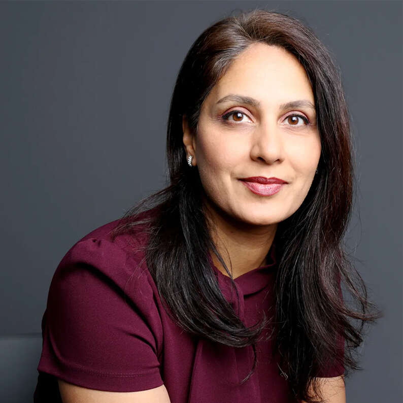 Dr. Nita Chhinzer poses for a photo in front of a dark grey backdrop