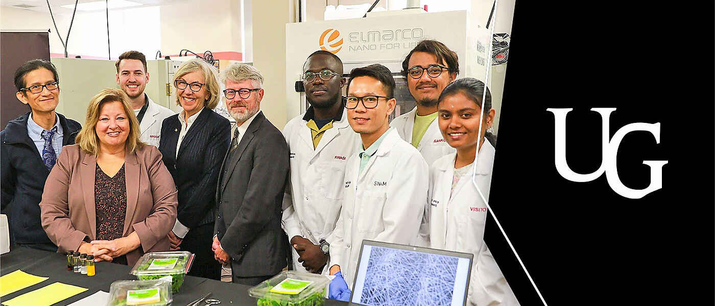 Dr. Loong-Tak Lim, minister of agriculture Lisa Thompson, president Dr. Charlotte Yates and Dr. Malcolm Campbell, vice-president (research) stand with several U of G student researchers in lab coats in a food science lab