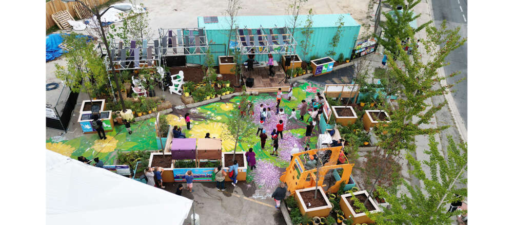 An aerial view of a plazaPOPs installation with brightly painted ground and several people walking among planters of plants and trees