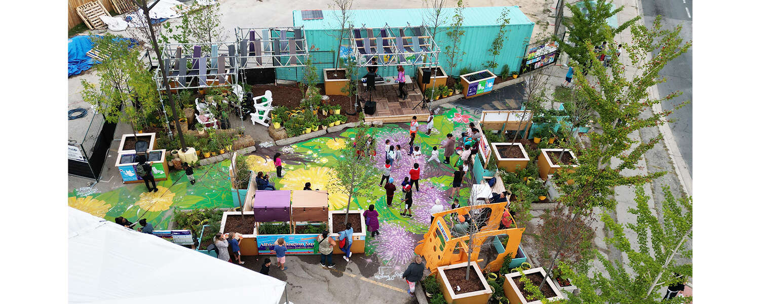 An aerial view of a plazaPOPs installation with brightly painted ground and several people walking among planters of plants and trees