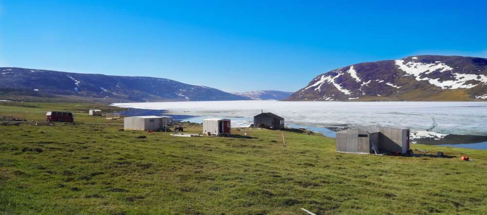 white and brown houses near ice filled water and mountain under blue sky
