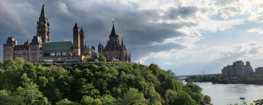Parliament building overlooking the Ottawa River under white clouds