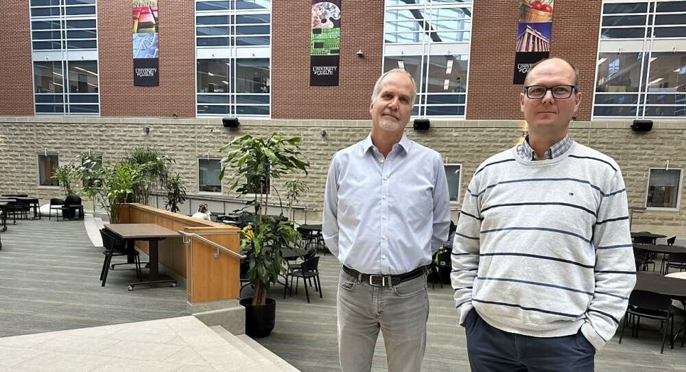 Two men stand in the atrium of the Summerlee Science complex on the U of G campus