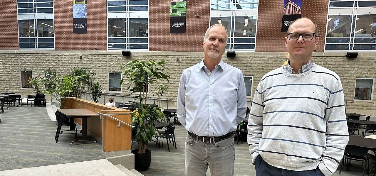 Two men stand in the atrium of the Summerlee Science complex on the U of G campus