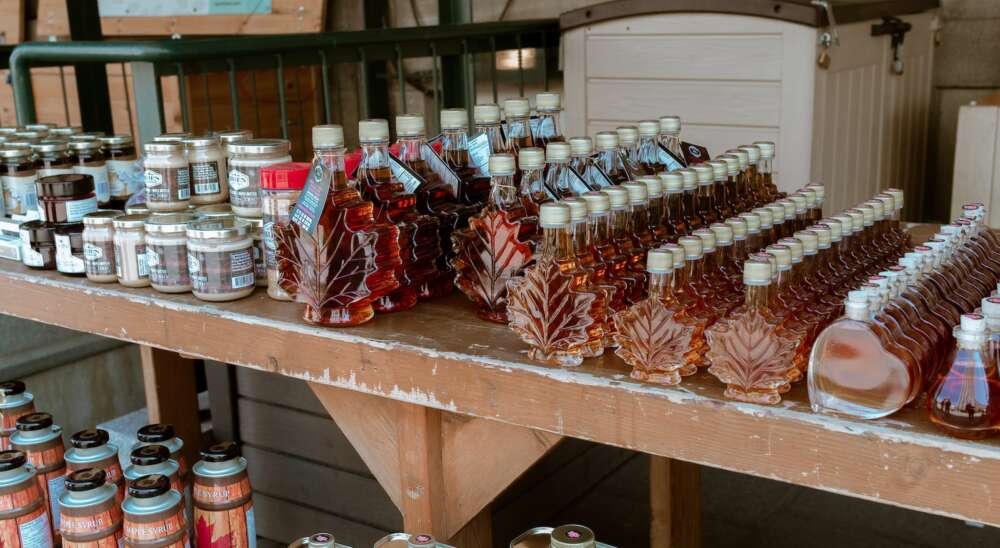 assorted glass bottles of maple syrup on wooden shelves