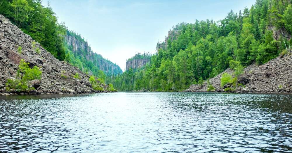a wide river with conifer-covered cliffs on either side