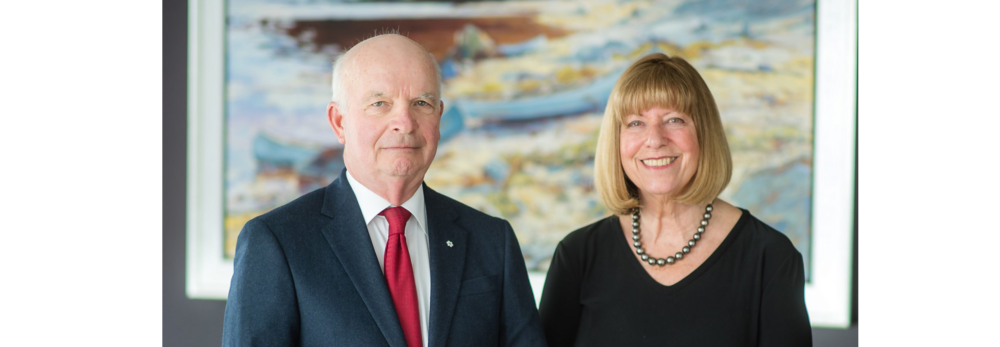 Tony and Anne Arrell smile for the camera while standing in a boardroom