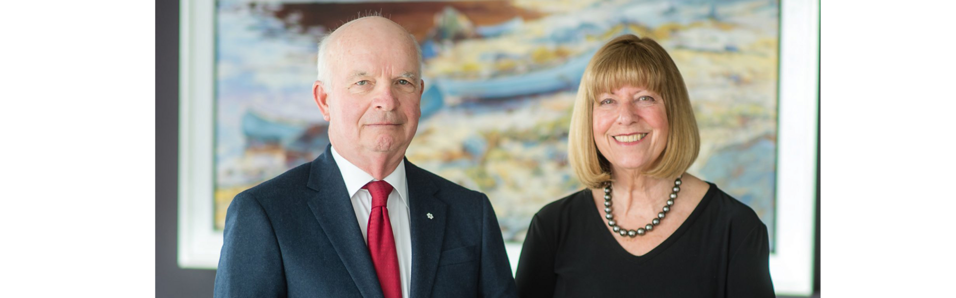 Tony and Anne Arrell smile for the camera while standing in a boardroom