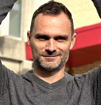 Dr. Allan McDougall poses for a photo while holding a soccer ball above his head