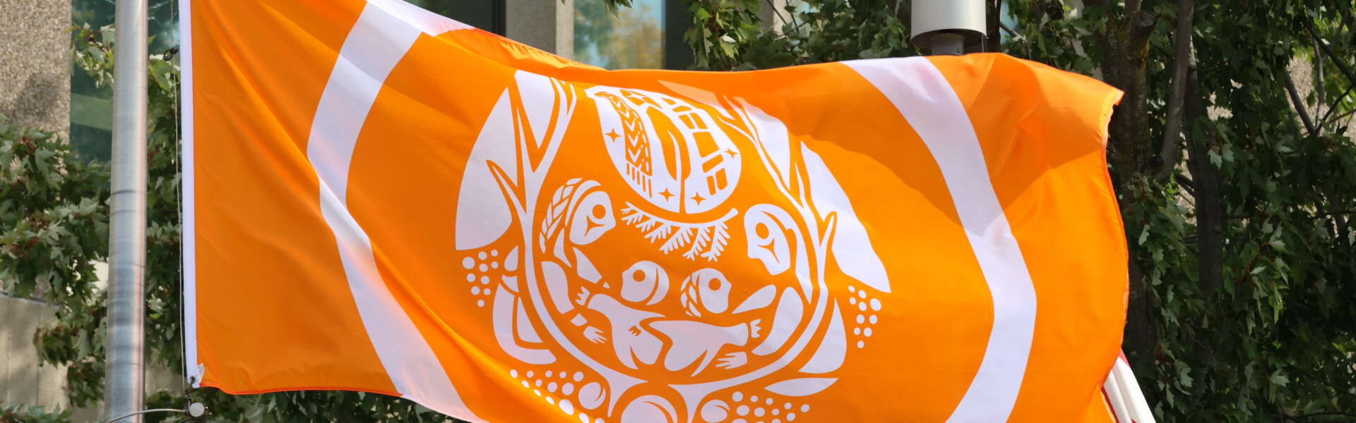 A closeup of an orange survivors flag portraying children reaching for adults