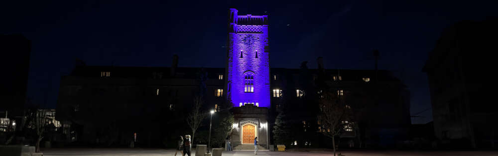 Johnston Hall on the U of G campus is illuminated in purple lights at night.