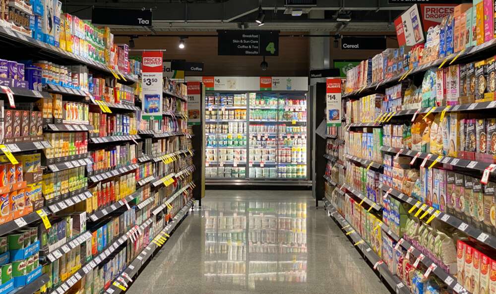 an aisle of a grocery store looking onto the refrigerated section
