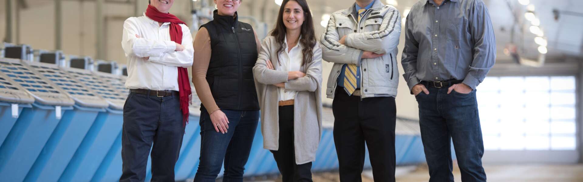 Five people pose for a photo standing in a large dairy barn