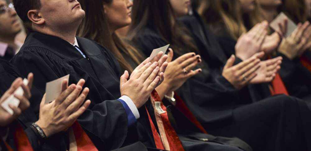 A zoomed-in shot of a row of hands clapping at a convocation ceremony