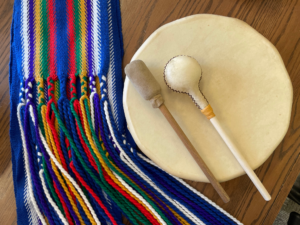 A traditional drum next to a colourful knotted fabric.
