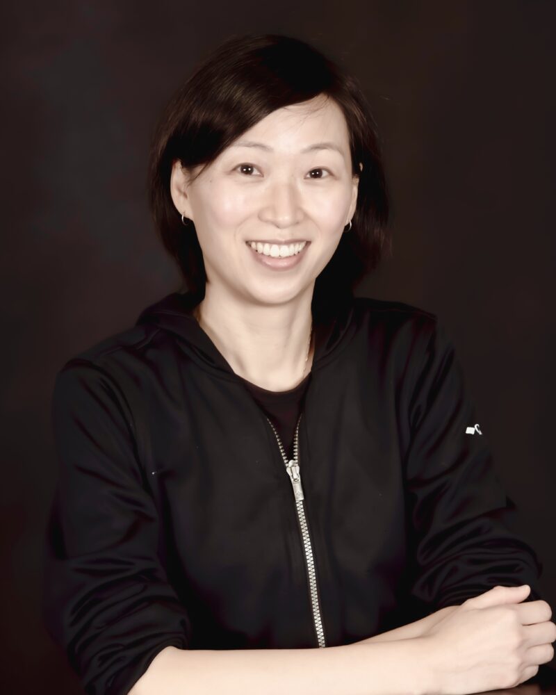 a woman in a black jacket poses for a headshot