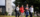 Four students walk in a line smiling at each other, wearing University of Guelph sweaters, against a campus background.