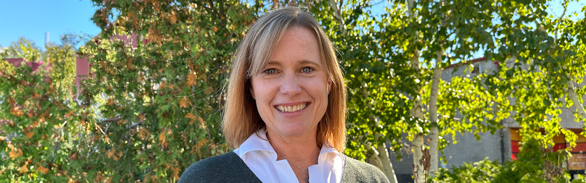 Headshot of Dr Joanne O’Meara, smiling and wearing a green sweater, with a garden background