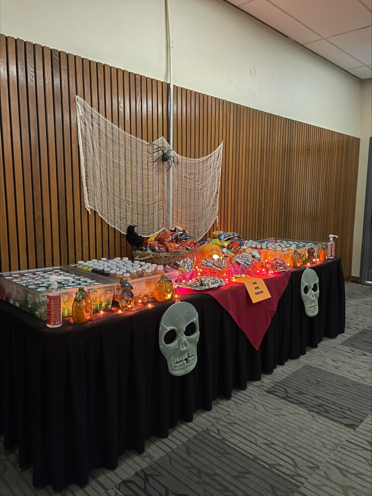 A table of halloween treats decorated with skulls and cobwebs.