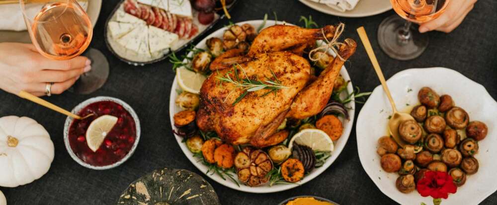 A delicious Thanksgiving feast featuring roasted chicken, wine, and seasonal sides. Top view.