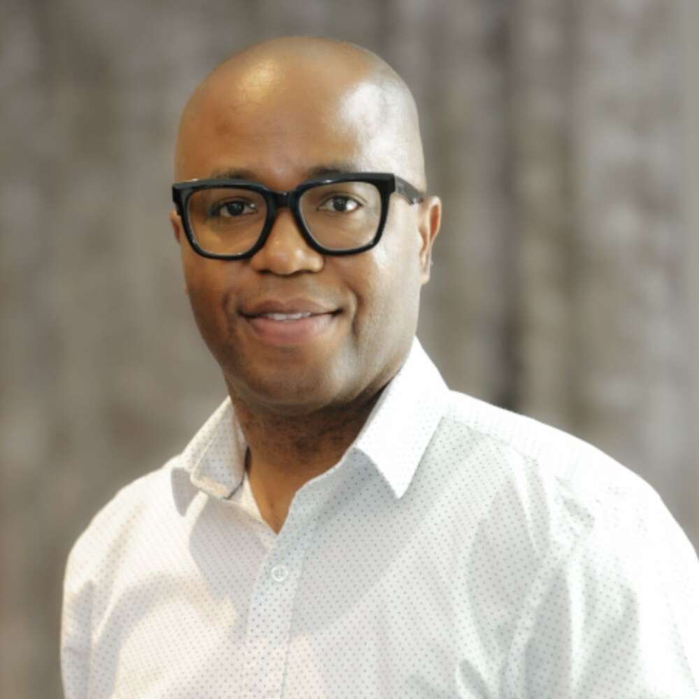 a man in glasses and a white shirt poses for a head shot