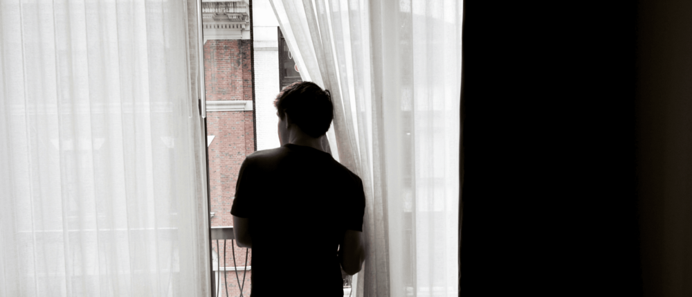 Silhouette of a person looking out of a window