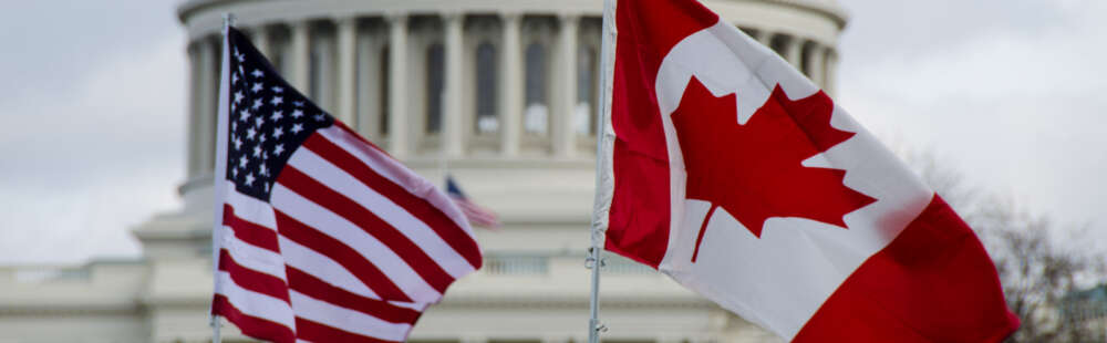 an american and canadian flag fly in front of the us capitol