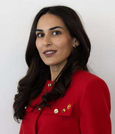 a woman in a red jacket with long black hair poses for a headshot