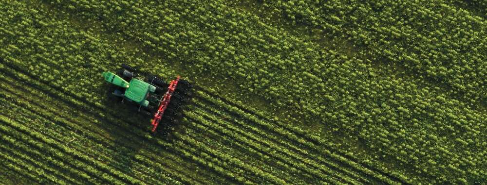 An aerial view of a tractor on a bright green field