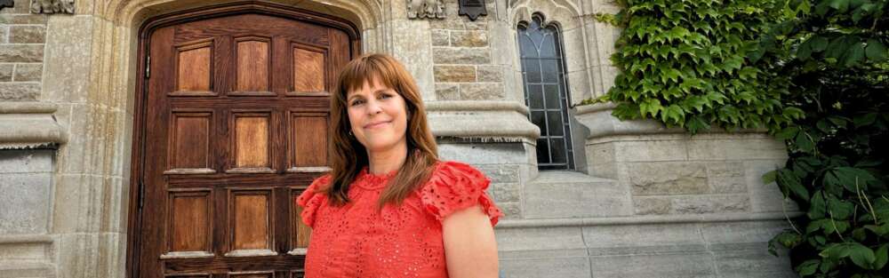 Kelly Hughes stands near a university building