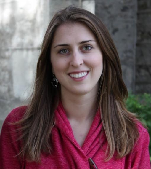 a person with long hair in a bright pink top poses for a headshot