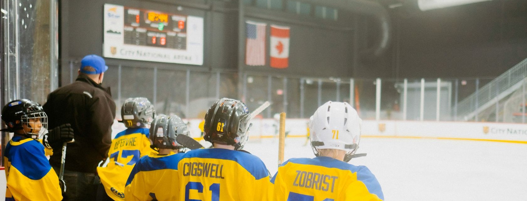 A hockey arena and the backs of the heads of young players on the bench