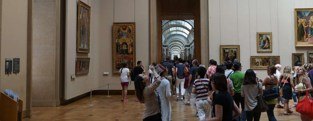 dozens of visitors look at paintings in a louvre gallery room