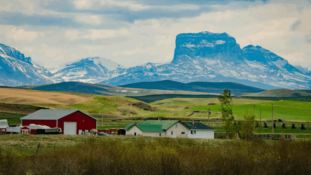 Serene mountain landscape with barn and house in foreground