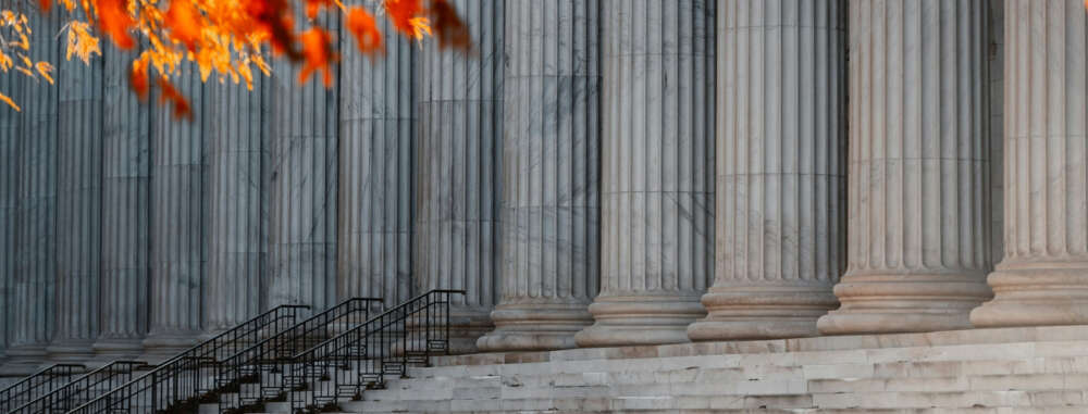 Marble columns framed by bright orange autumn leaves.