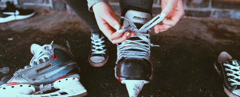 person in black and white adidas sneakers holding white smartphone