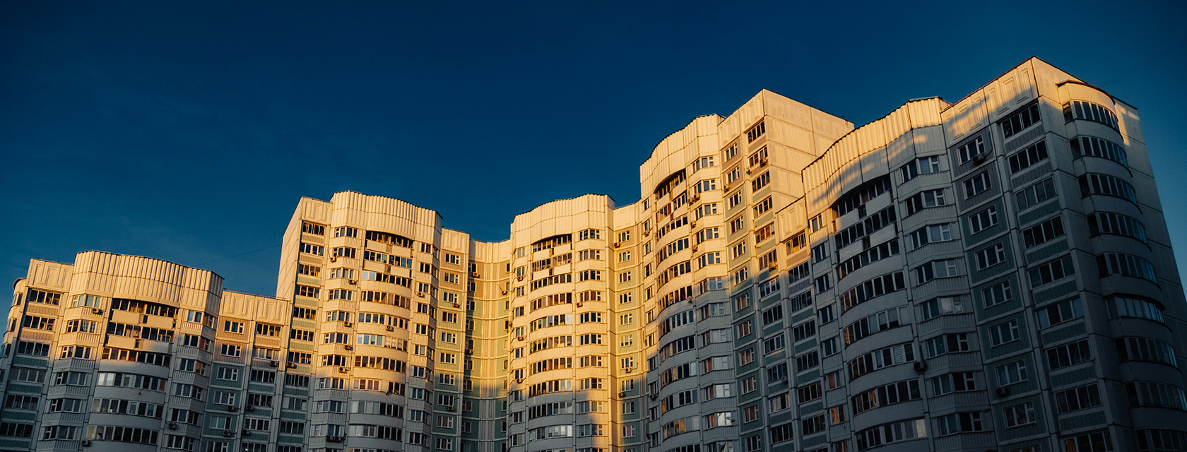 The tops of a large condo tower against a blue sky